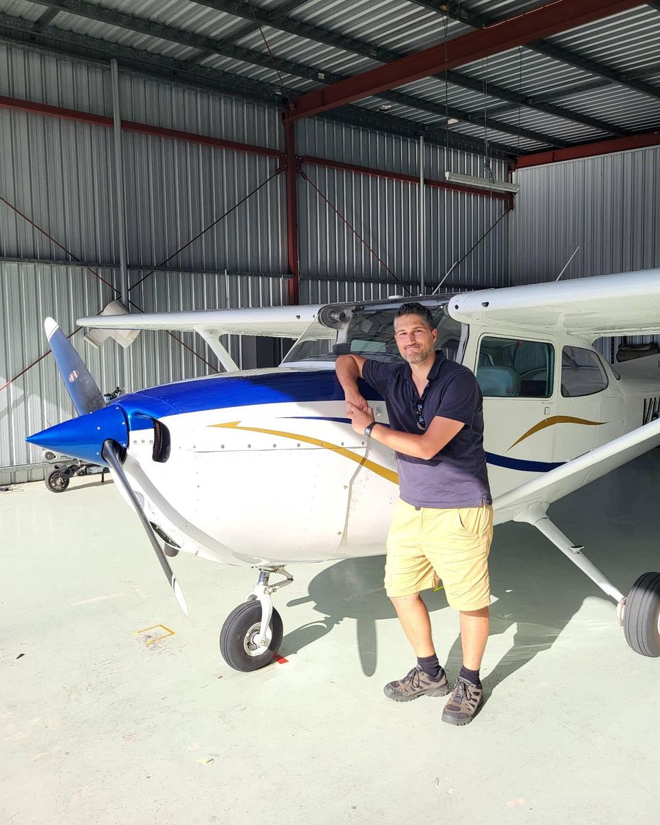 Jim leaning on the cowling of a single-engine Cessna in a hangar